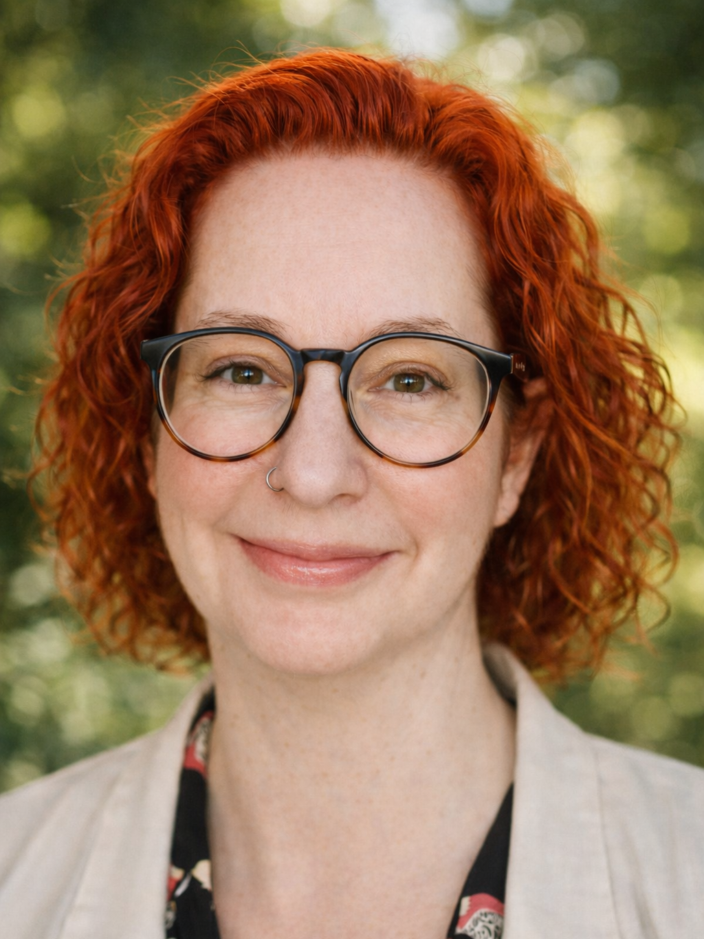 Headshot of a red head with glasses and hazel eyes.